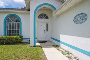 A house with a white exterior, blue trim, a front door, and a mailbox. - 3BR Home with Private Pool Minutes from Disney (Kissimmee)