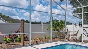 A backyard with a swimming pool, a hammock, and outdoor furniture. - 3BR Home with Private Pool Minutes from Disney (Kissimmee)