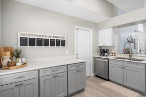 A modern kitchen with grey cabinetry, a white countertop, a built-in oven, and a coffee maker. - 3BR Home with Private Pool Minutes from Disney (Kissimmee)