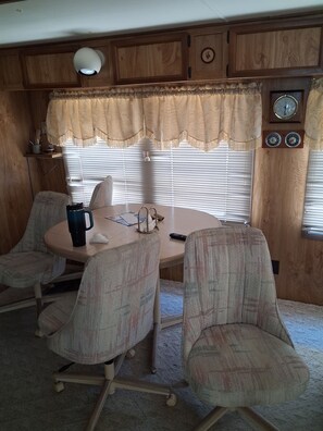 A dining area with a round table, four chairs, a coffee pot, and a clock on the wall. - Beautiful 1-bedroom mobile home with AC in Jensen Beach (Jensen Beach)