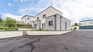 A modern two-story residential building with a flat roof, a driveway, and a landscaped garden area. - Architect-designed house 800m from the sea (Paimpol)