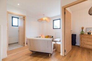 A modern bedroom with a bed, bedside table, lamp, and a dresser. - Architect-designed house 800m from the sea (Paimpol)