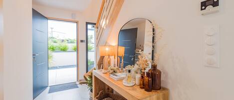 A modern hallway with a wooden console table, a mirror, and a door leading outside.