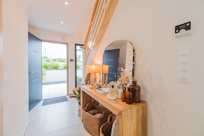 A modern hallway with a wooden console table, a mirror, and a door leading outside. - Architect-designed house 800m from the sea (Paimpol)