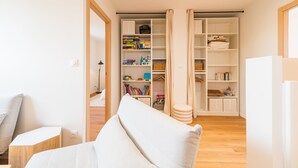 A modern living room with a sofa, a small table, and a bookshelf filled with books and games. - Architect-designed house 800m from the sea (Paimpol)
