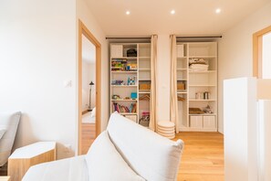 A modern living room with a sofa, a small table, and a bookshelf filled with books and games. - Architect-designed house 800m from the sea (Paimpol)