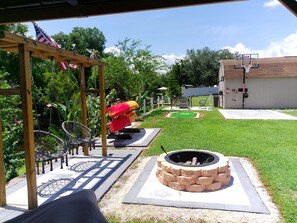Ein Garten mit einer Holzpergola, einer Feuerstelle, einem Basketballkorb und einem Kajak.