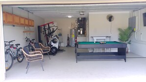 Garagem com mesa de bilhar, equipamentos de ginástica e bicicletas.