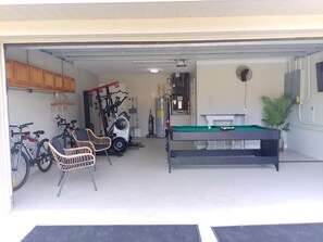 Eine Garage mit Billardtisch, Trainingsgeräten und Fahrrädern.