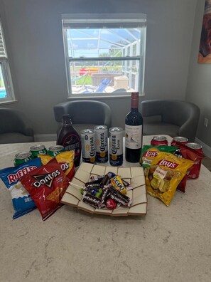 Ein Tisch mit Snacks, Getränken und einer Weinflasche in einem Zimmer mit Fenster.