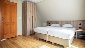 A bedroom with a bed, wooden wardrobe, and a hanging light fixture. - Texel Nature Villa With Sauna (De Koog)