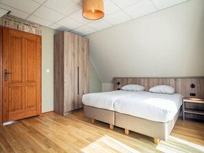 Ein Schlafzimmer mit Bett, Holzschrank und einer Pendelleuchte.