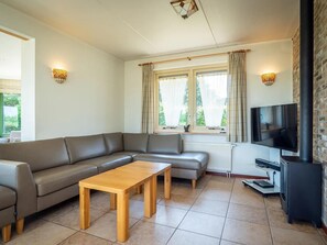 A modern living room with a sectional sofa, a wooden coffee table, a flat-screen TV, and a fireplace. - Texel Nature Villa With Sauna (De Koog)