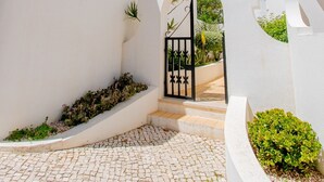 A white building with a paved courtyard and a black gate. - 2 mins walk to Carvoeiro beach, Amazing Pool, Aircon, newly renovated, Fast WiFi (Carvoeiro)