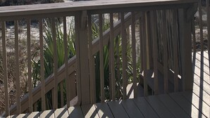 Una terraza de madera con vista a la playa y al océano.