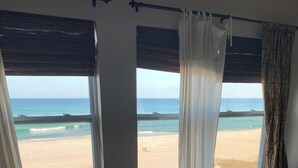 Un dormitorio con cama, dos ventanas vistas al mar y piso alfombrado.