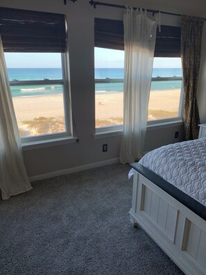 A bedroom with a bed, two windows with beach views, and a carpeted floor. - Beachside townhome on the beach  (Panama City Beach)