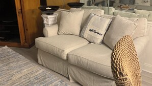 Una sala de estar con un sofá, un tapete estampado y una silla de mimbre.