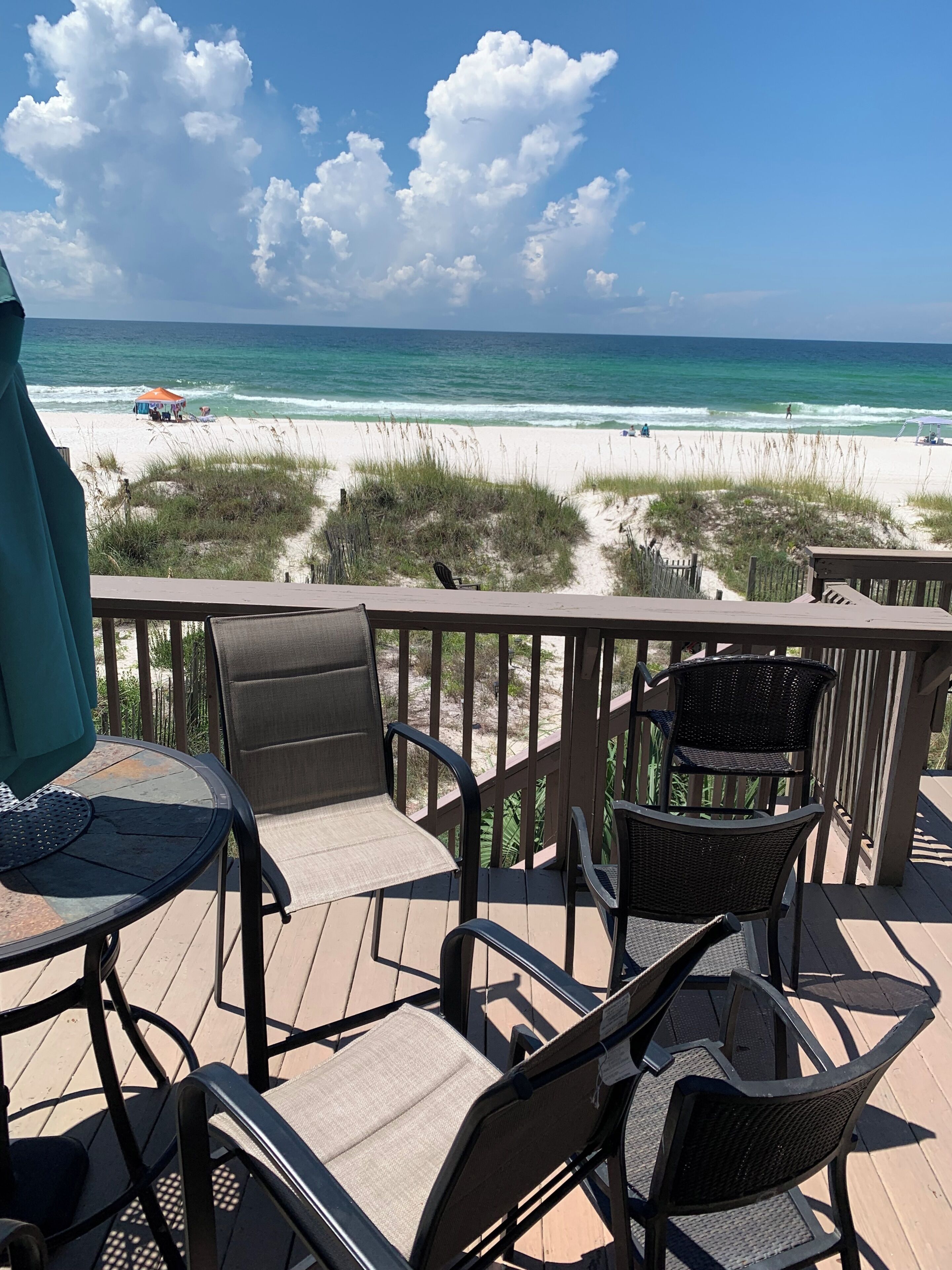 A deck with outdoor seating overlooking a beach.