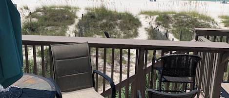 A deck with outdoor seating overlooking a beach.
