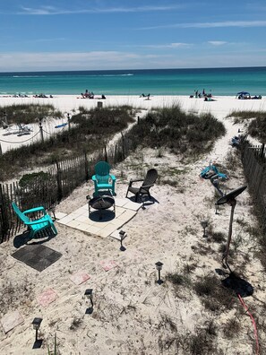 A beach with a sandy area featuring a fire pit, chairs, and a solar lamp. - Beachside townhome on the beach  (Panama City Beach)
