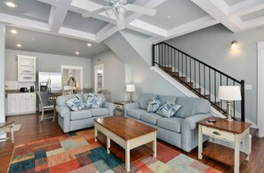 A spacious living area with a sofa set, coffee table, and a patterned rug. A staircase with a railing is visible in the background. - Spacious 3-bedroom apartment in beautiful Branson with AC and gym (Branson)