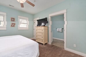A bedroom with a bed, dresser, television, and a door leading to a bathroom. - Spacious 3-bedroom apartment in beautiful Branson with AC and gym (Branson)