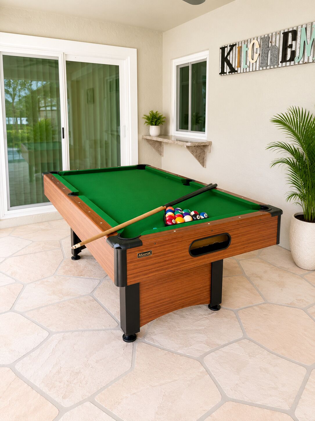 A pool table with a wooden frame and a green felt surface, positioned on a tiled floor.