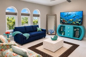 A living room with a blue sofa, a television, and a teal cabinet.