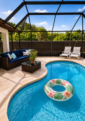 A backyard with a swimming pool, a covered seating area with a sofa and chairs, and a wooden fence. - Tu hogar lejos de Casa..4BR..POOL ..PET Friendly ! (Port Charlotte)