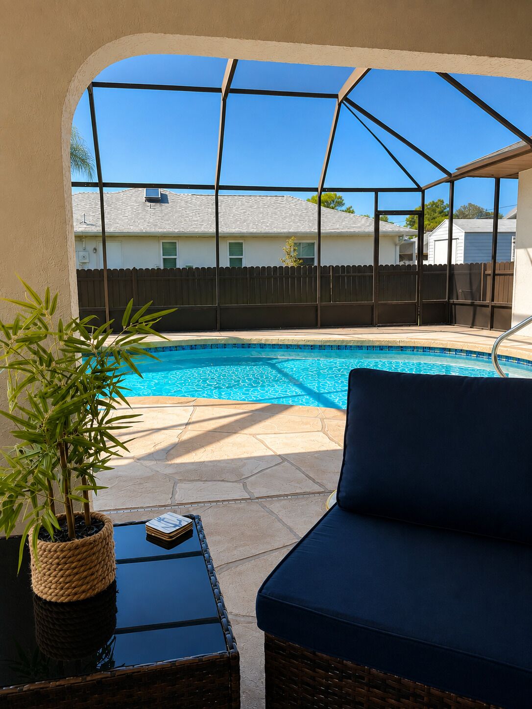 Ein Garten mit Schwimmbad, einer überdachten Terrasse und Blick auf Nachbarhäuser.