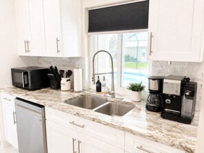 A modern kitchen with white cabinets, a double sink, a coffee machine, and a dish soap dispenser. - Tu hogar lejos de Casa..4BR..POOL ..PET Friendly ! (Port Charlotte)
