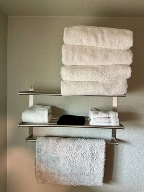 A bathroom with a towel rack holding several neatly folded towels. - Angry Salmon Inn Room 25 (Anchor Point)