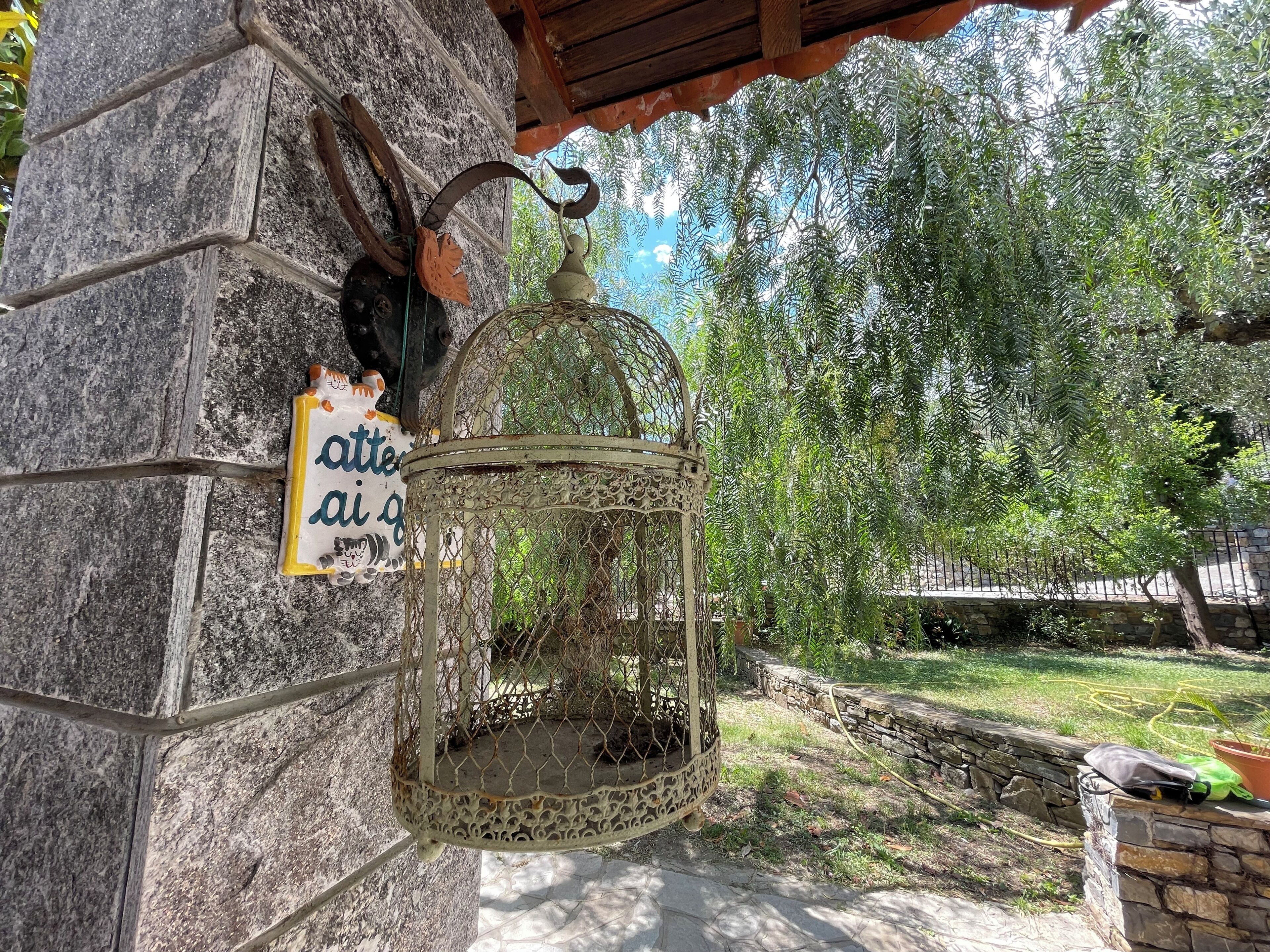 Paredes de pedra com uma gaiola de pássaro pendurada e uma placa.