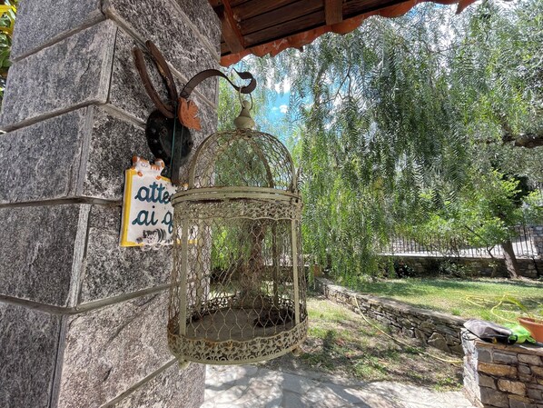 Un mur de pierre avec une cage à oiseaux suspendue et une enseigne.