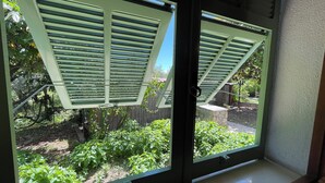 Ein Fenster mit Blick auf einen Garten und einen Holzzaun.