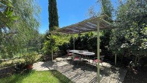 Ein Patio mit Pergola, Steinmauer und Kübelpflanzen.