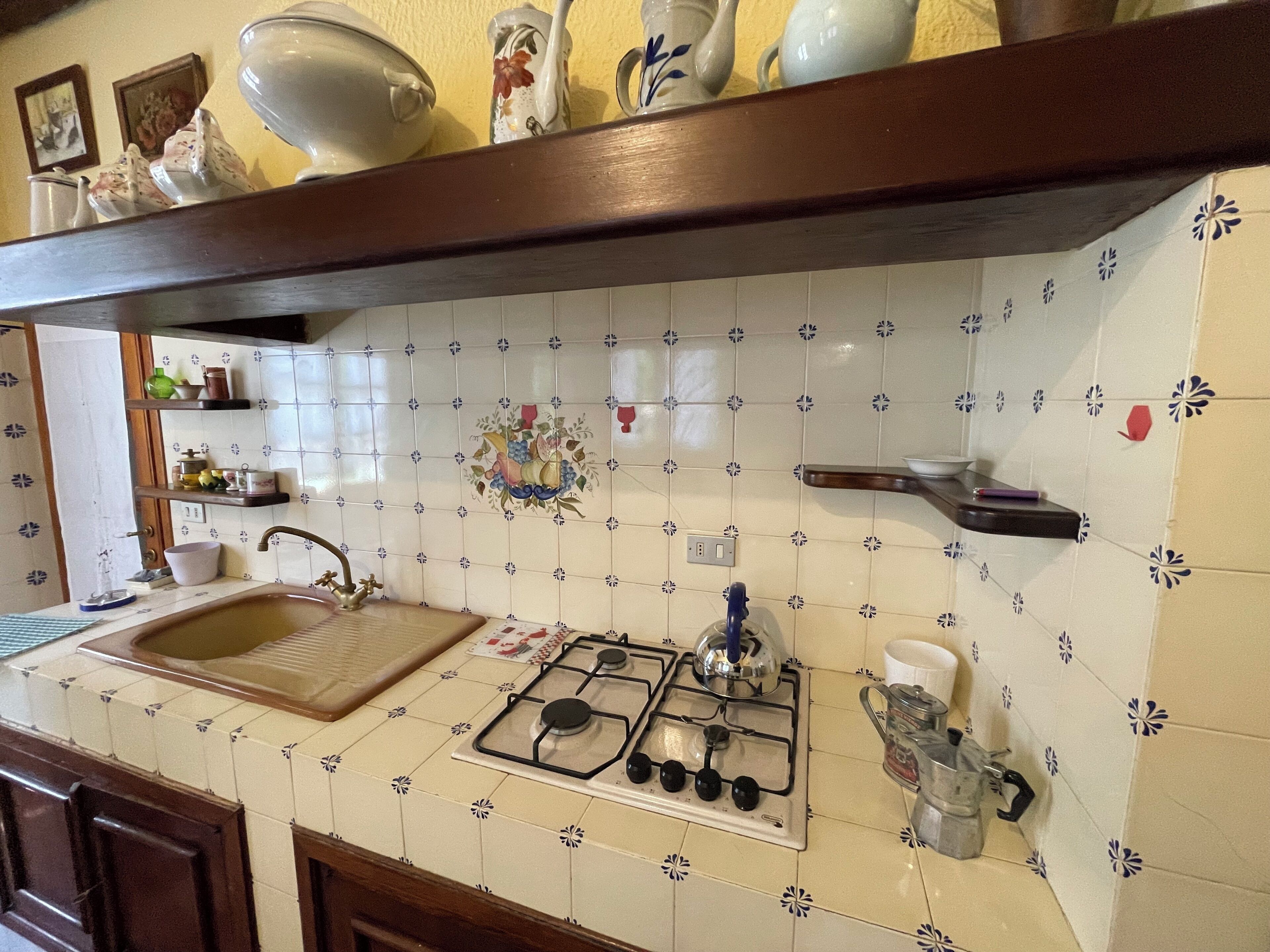 A kitchen with a gas stove, a sink, and a tiled backsplash.