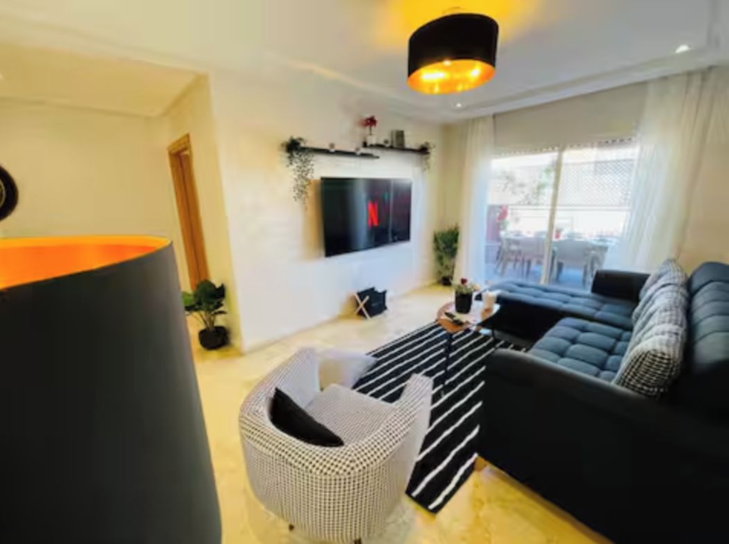 A modern living room with a sofa, a TV mounted on the wall, and a lamp.