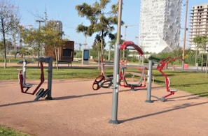 An outdoor exercise area with various fitness equipment, a bench, and a tall building in the background. - 2 min from Finance City + Fiber + 110 m² + Free Parking + PS4 + IPTV (Casablanca)