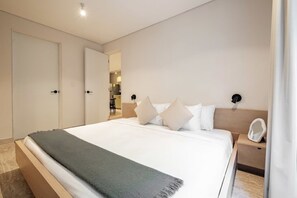 A modern hotel room with a large bed, a bedside table, and a nightstand. - CAM 1-Bedroom Deluxe (Ciudad de México)