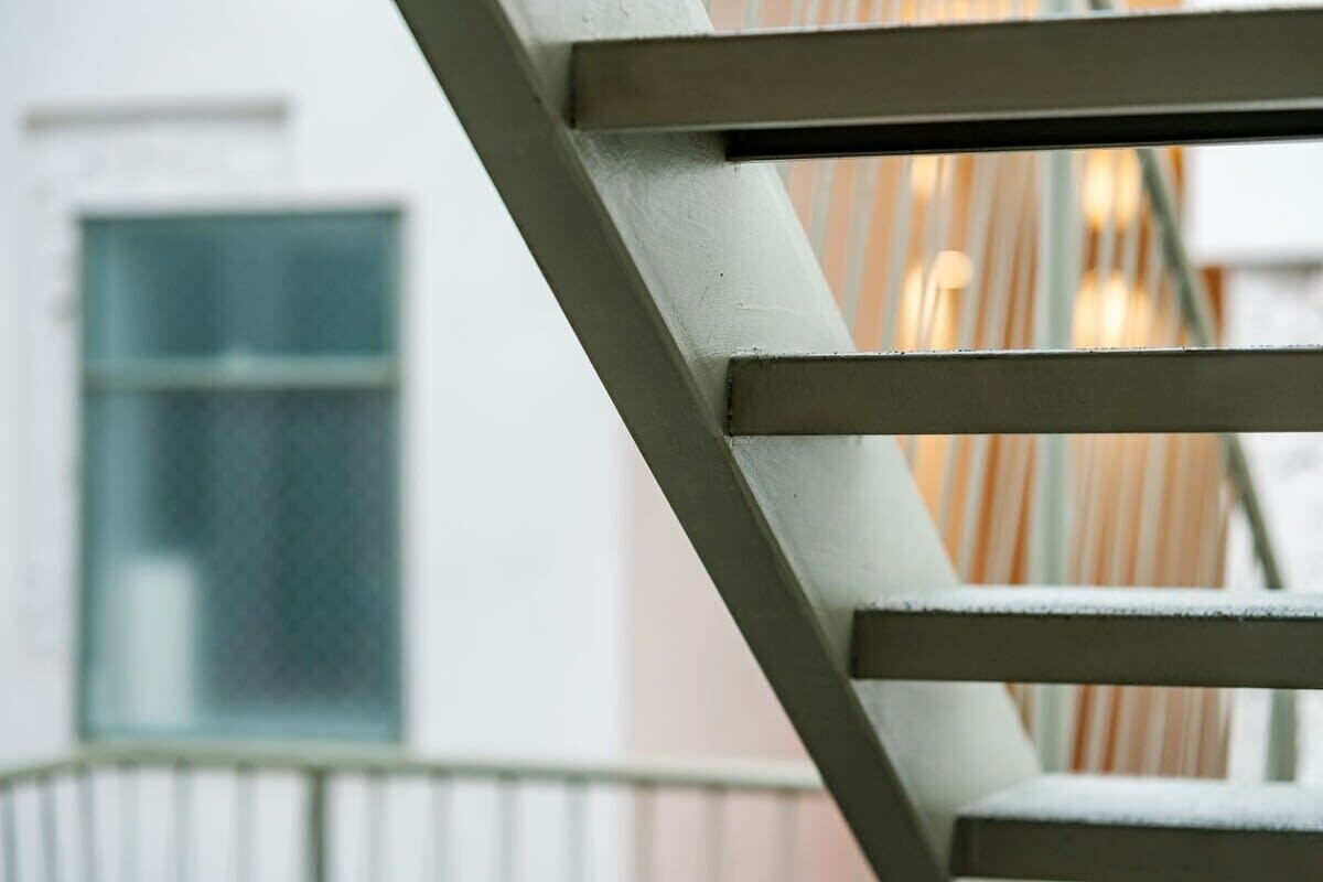 A close-up of a white metal staircase railing with a blurred background.