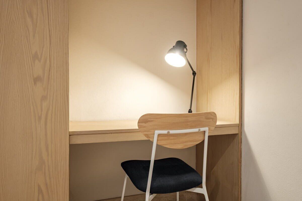 Ein Holztisch mit einem weißen Stuhl, einer schwarzen Schreibtischlampe und einer Wand mit einer Holzverkleidung.