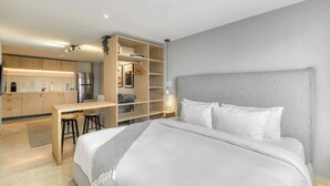 Ein modernes Hotelzimmer mit Bett, Schreibtisch und einer Küchenzeile.