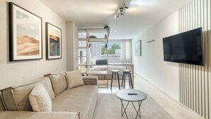 A modern living room with a sofa, a coffee table, a TV, and artwork on the walls. - Modern King Studio in Central Roma Norte (Ciudad de México)