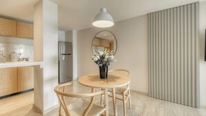 A modern kitchen with wooden cabinets, a stainless steel refrigerator, and a round dining table with chairs. - Modern King Studio in Central Roma Norte (Ciudad de México)
