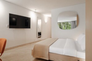 Ein modernes Hotelzimmer mit einem Bett, einem an der Wand montierten Fernseher, einem Spiegel und Blick auf Grünflächen.