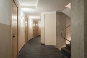 A corridor with wooden doors, a concrete staircase, and a tiled floor. - Modern Loft with Balcony & View of Parque Mexico (Ciudad de México)
