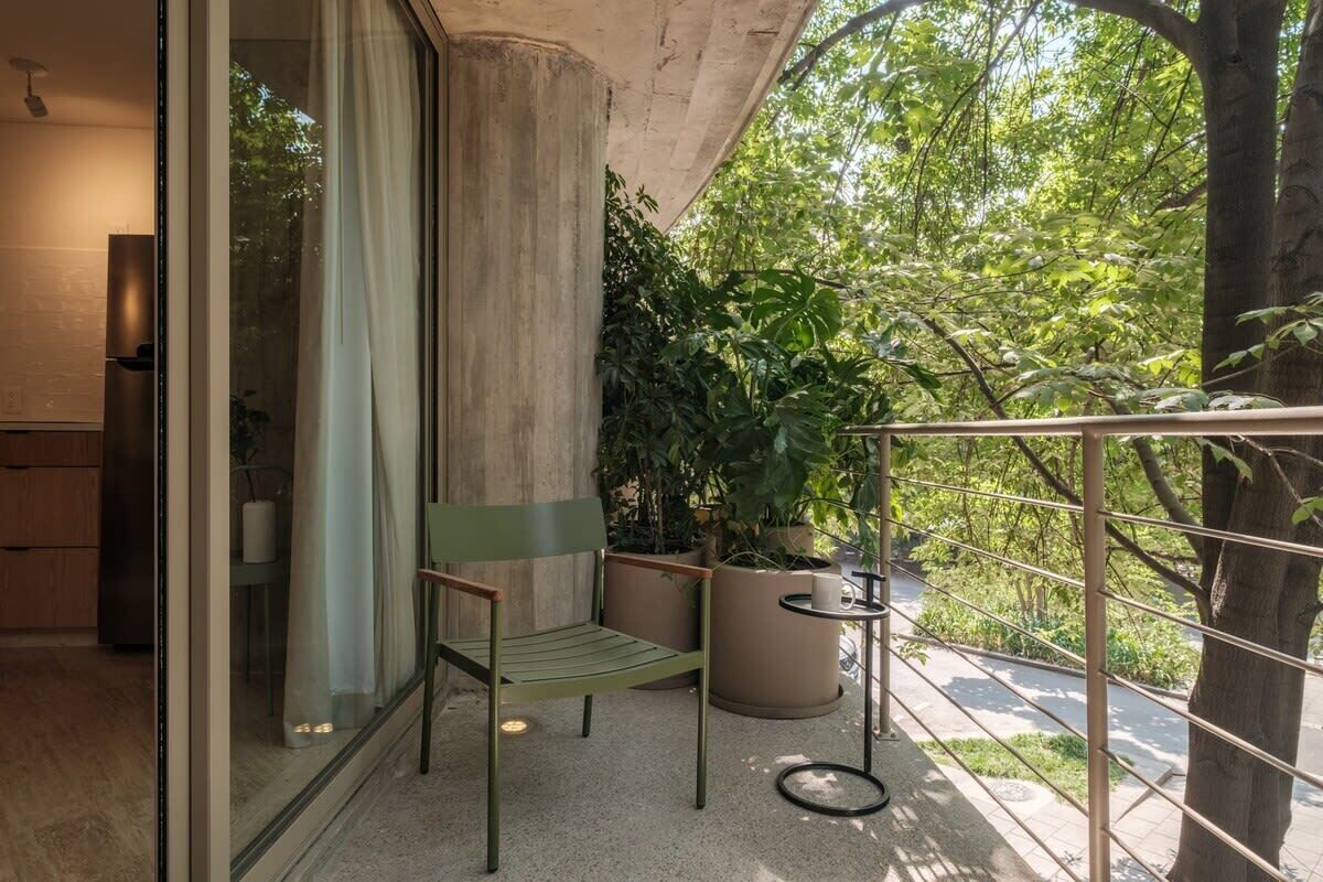 A balcony with a chair, a small table, and potted plants.