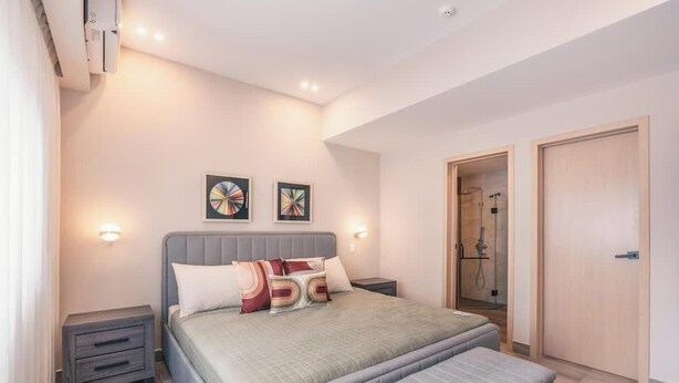 A modern bedroom with a bed, bedside tables, wall art, and a walk-in closet. - Flat in Regatta Ii with breakfast included 204 (Santo Domingo)